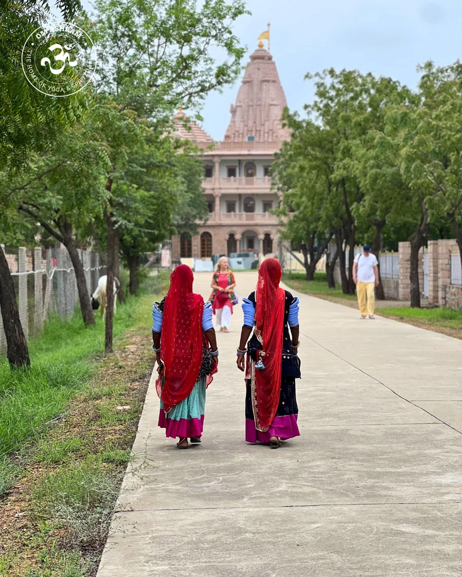 Women in sarees with the OM Ashram building in the background.
